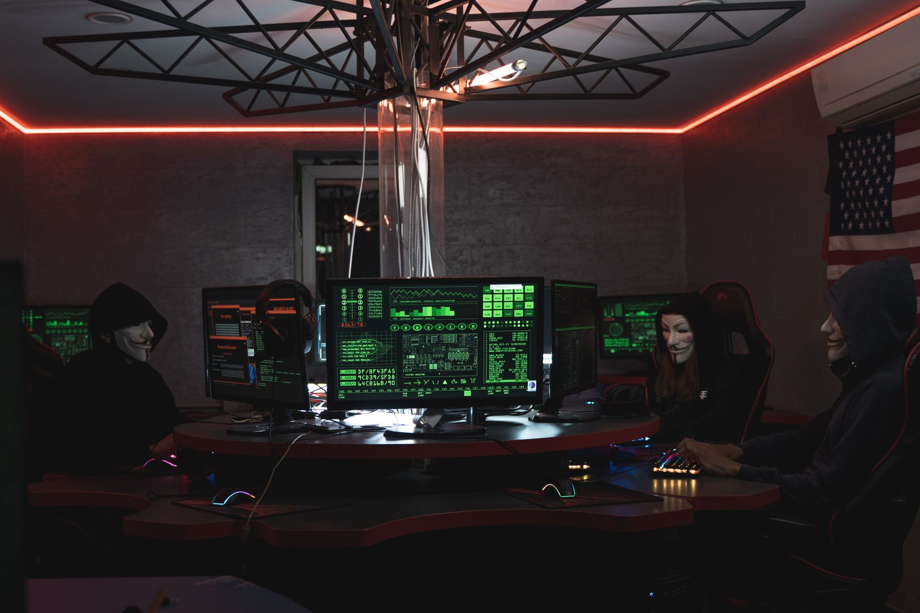 Hooded hacker coding in a dark room
